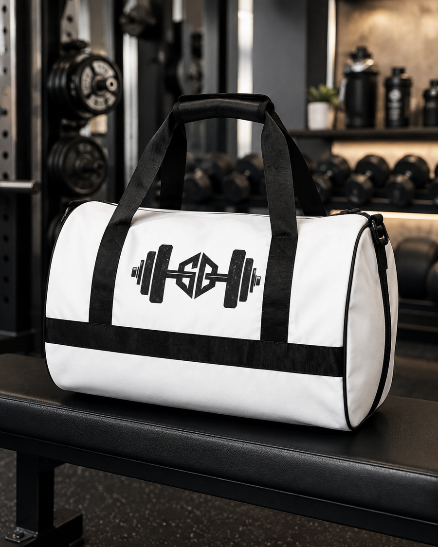 White gym duffel bag with black barbell logo displayed on a bench in a weightlifting gym